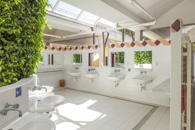 Bagni pubblici luminosi con specchi e lavandini.