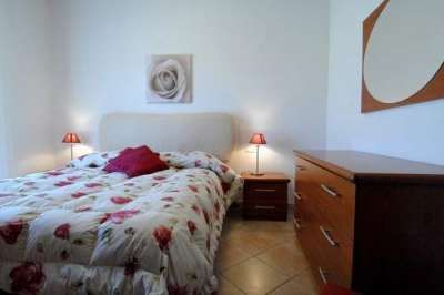 Camera da letto con letto matrimoniale, abat-jour e pareti bianche.