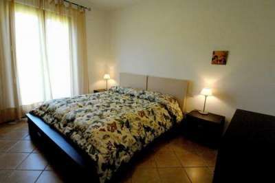Camera da letto con letto matrimoniale, copripiumino a fantasia floreale e due lampade sui comodini.