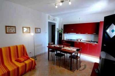 Soggiorno con divano a righe arancioni e cucina rossa.