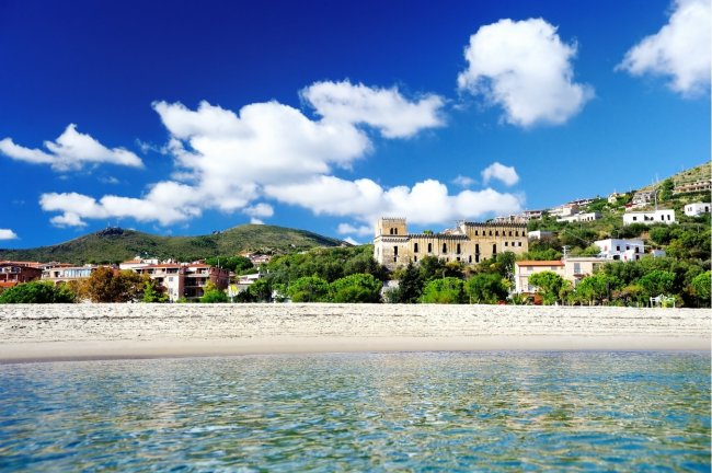 Spiaggia con edificio storico sullo sfondo.