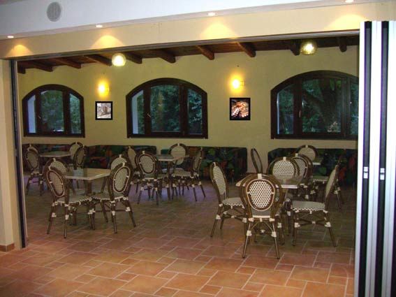Interno di un caffè con sedie in stile bistrot, finestre grandi e luci soffuse.