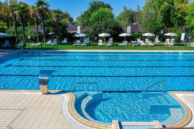 Piscina con getto d'acqua e ombrelloni.