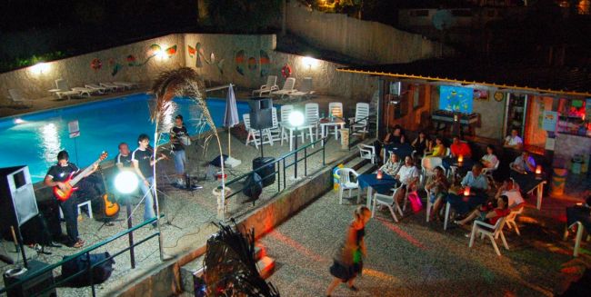 Band suona vicino a una piscina con pubblico seduto.