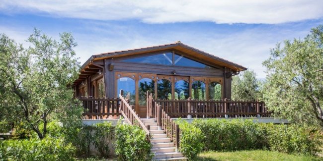 Casetta di legno con ampie finestre e giardino.