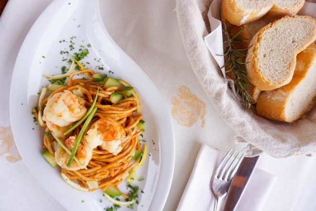 Piatto di pasta con gamberi e pane.