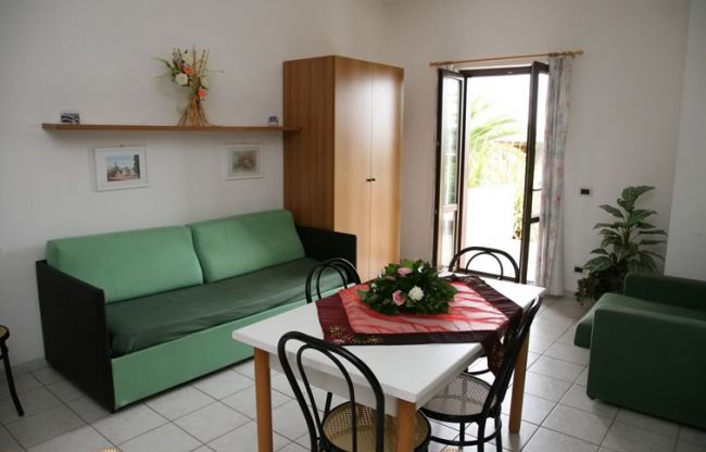 Soggiorno con divano verde e tavolo da pranzo.