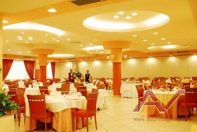 Una sala ristorante elegante con tavoli apparecchiati e sedie rosse.