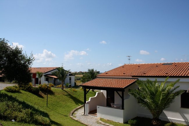 Ville con tetti rossi tra prati verdi.