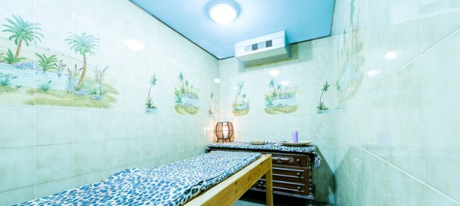 Stanza massaggi con lettino e decorazioni tropicali.