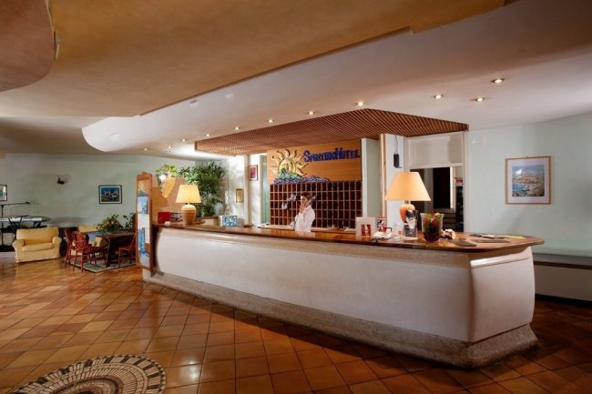 Reception di un hotel con banco e receptionista.