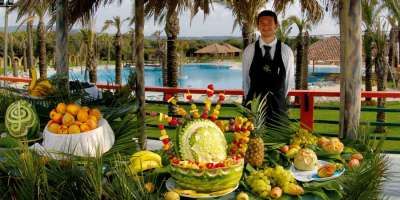 Un tavolo decorato con frutta intagliata, all'aperto vicino a una piscina.