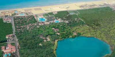 Vista aerea di un'area con laguna, piscine e vegetazione vicino alla spiaggia.