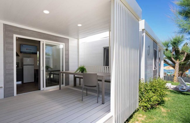 Veranda con tavolo, sedie e giardino.