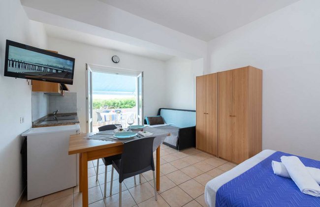 Monolocale con cucina, TV e terrazza.