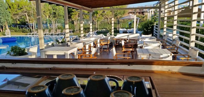 Area bar con tavoli bianchi vicino a una piscina.