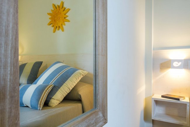 Riflesso di una camera con cuscini a righe blu e giallo dietro un specchio.