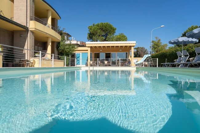 Piscina blu con edificio giallo sullo sfondo.