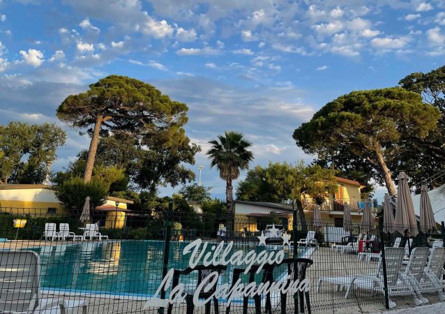 Piscina all'aperto con sedie a sdraio e alberi.