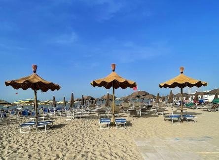 Spiaggia con lettini e ombrelloni di paglia.