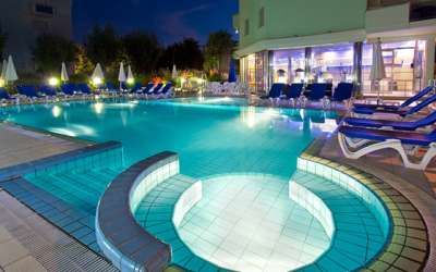 Piscina di notte con gradini curvi, sedie a sdraio e ombrelloni.