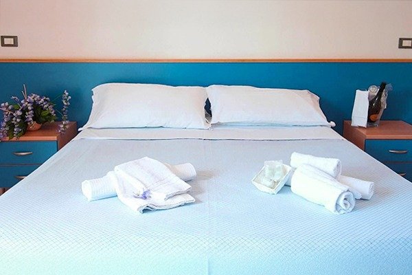 Letto matrimoniale con asciugamani bianchi.