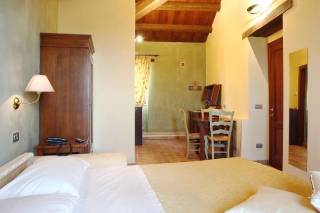 Camera con letto, armadio in legno e tavolo vicino alla finestra.