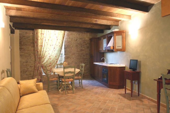 Soggiorno con divano, tavolo da pranzo e cucina rustica.
