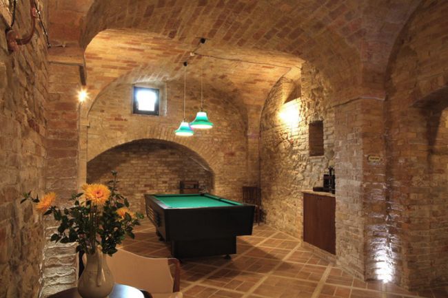 Sala giochi con tavolo da biliardo in una stanza in pietra.