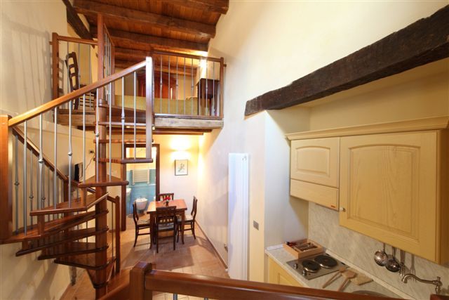 Scala a chiocciola in un appartamento con cucina e sala da pranzo.