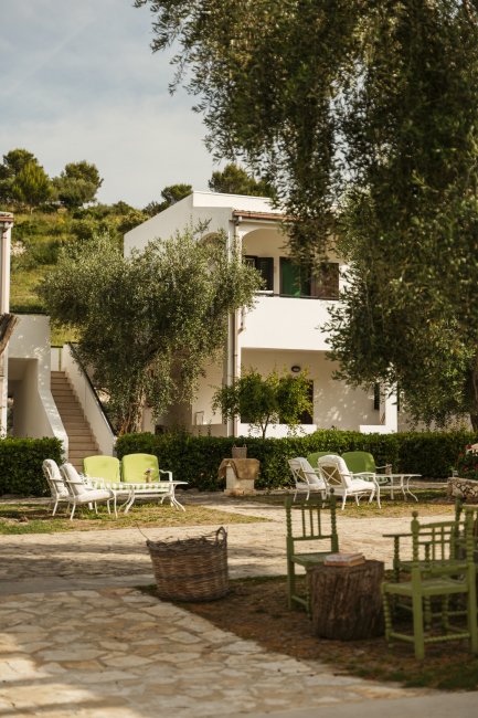 Un cortile di una villa con sedie bianche e verdi, circondato da alberi.