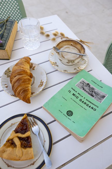 Colazione con dolci e libro su tavolo bianco.
