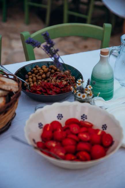 Tavola con pomodori, olive e pane, decorata con fiori.