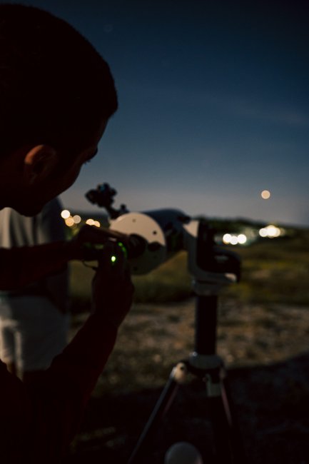 Persona che osserva al telescopio di notte.