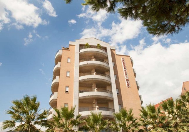Un edificio moderno con balconi e palme in primo piano.