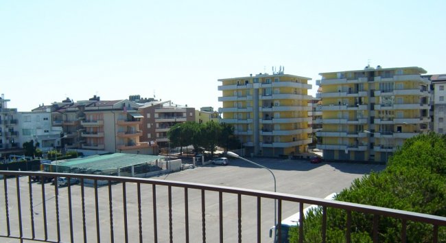 Vista da un balcone su edifici residenziali e spazi aperti.