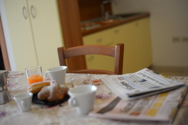 Tavolo da colazione con giornali, caffè e succo d'arancia.