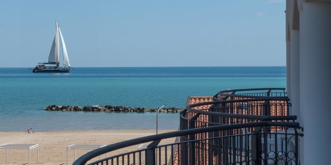Balcone fronte mare con barca a vela in lontananza.