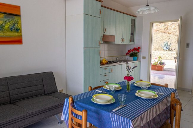 Cucina con tavolo apparecchiato e divano grigio.
