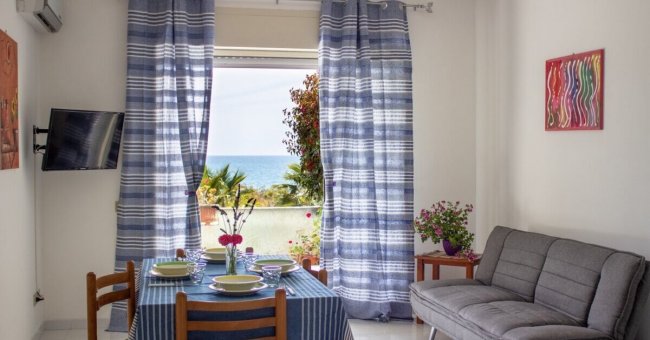 Soggiorno con tavolo apparecchiato e vista mare.
