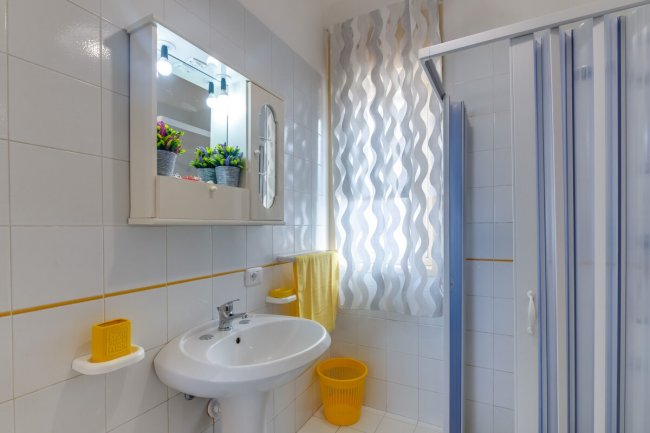 Bagno luminoso con doccia e lavandino.