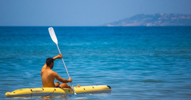 Persona su un kayak giallo in mare calmo.