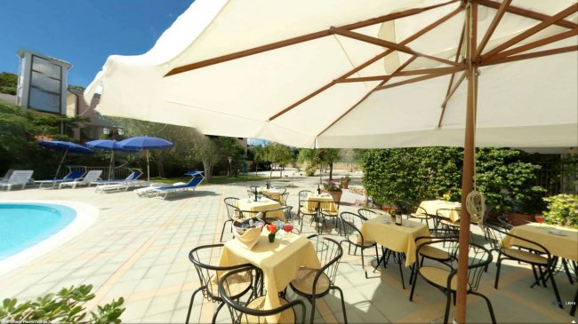 Tavoli con ombrelloni vicino alla piscina.