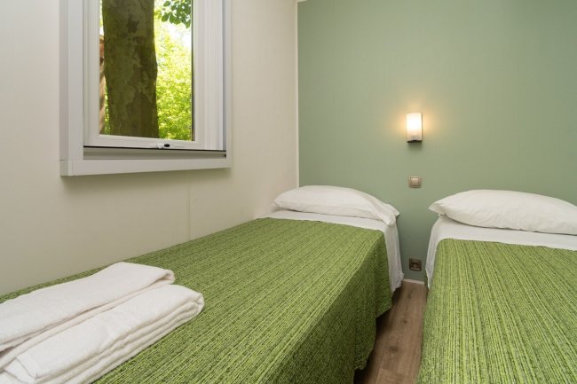 Camera con due letti singoli e parete verde.