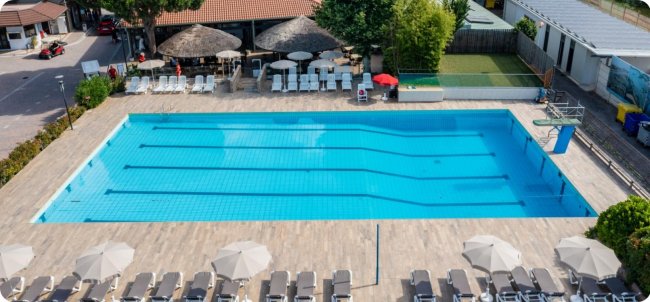 Piscina con sedie a sdraio e ombrelloni.