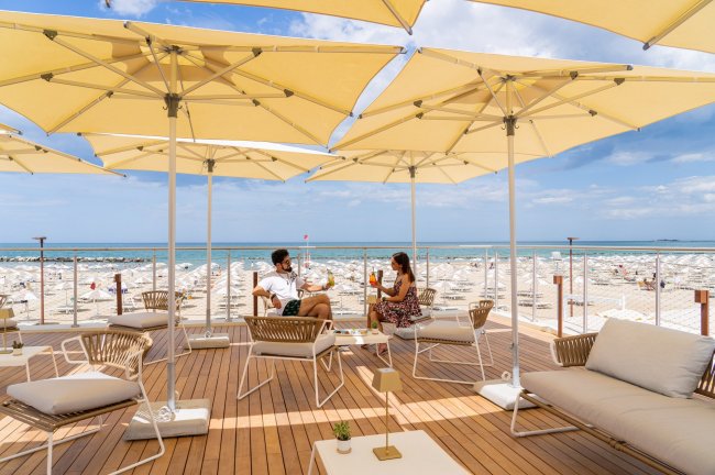 Terrazza con sedie e ombrelloni vista mare.