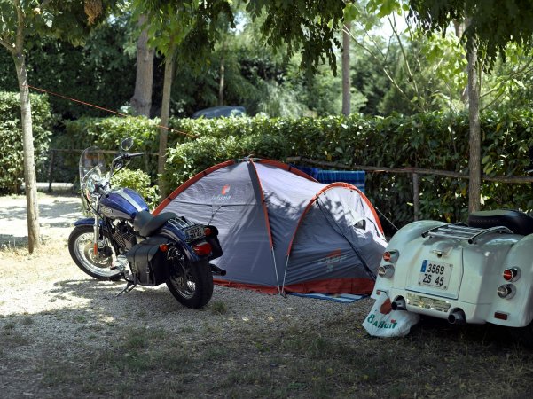 Tenda grigia con motocicletta e scooter parcheggiati.