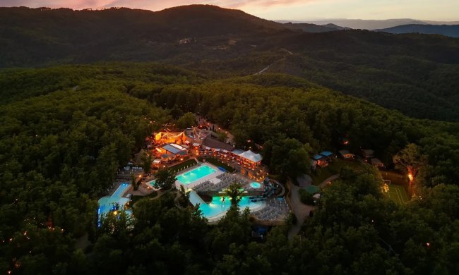 Veduta notturna di un resort con piscine illuminate.