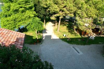 Vista dall'alto su un sentiero accanto a una casa con tetto rosso e alberi circostanti.