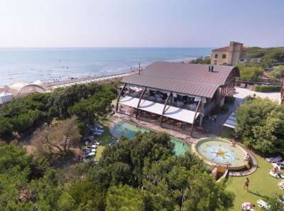 Vista aerea di un edificio con piscina vicino al mare e circondato da vegetazione.